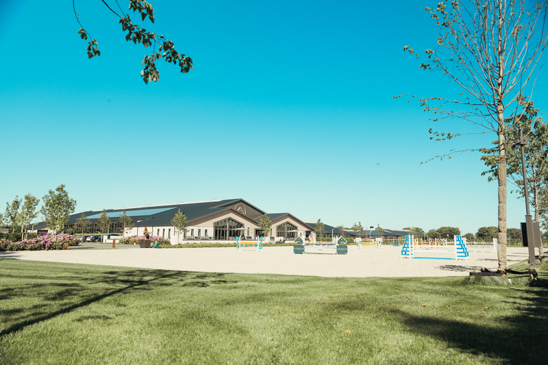 Model poseert naast een rijbak met springhindernissen