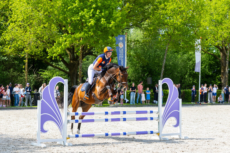 manegehouder sandra melten loopt naast een aantal ruiters met hun paard