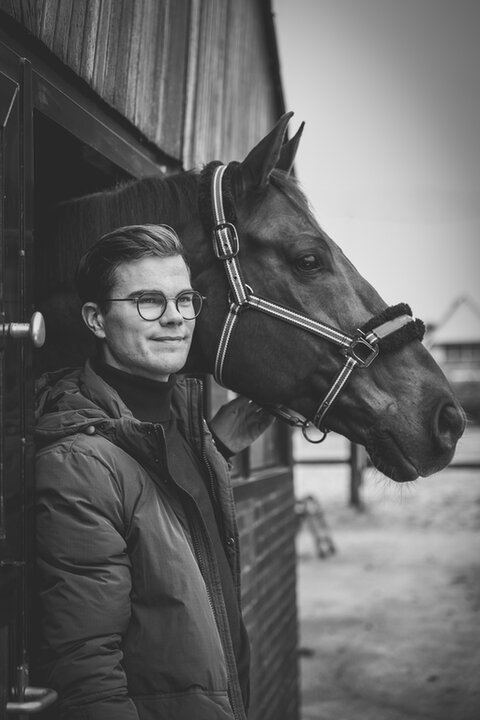 Marten staat naast zijn paard terwijl deze naar buiten kijkt