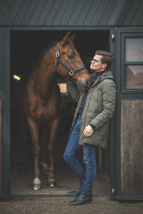 Marten Luiten staat bij zijn paard in de opening van de stal.