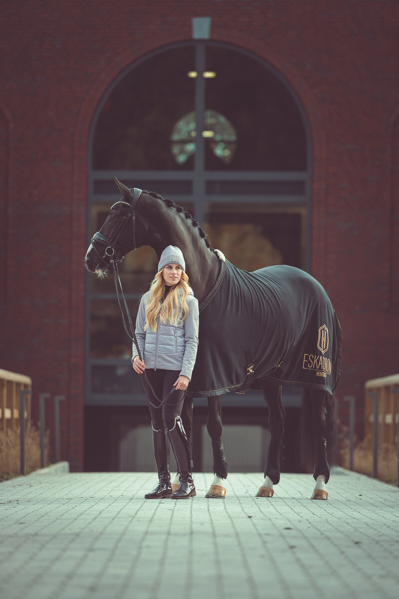 Model dominique is gekleed in kleding van pikeur, haar paard heeft een deken van eskadron