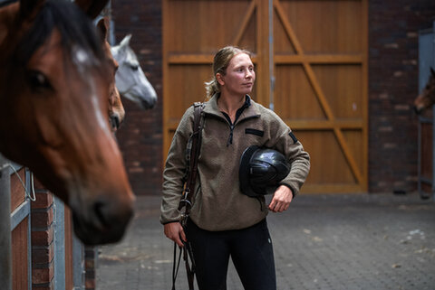 janneke boonzaaijer zit met een jack russel hondje op schoot in de zadelkamer