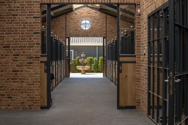 Model poseert naast een rijbak met springhindernissen